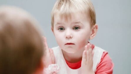 Little boy looking at his face in the mirror