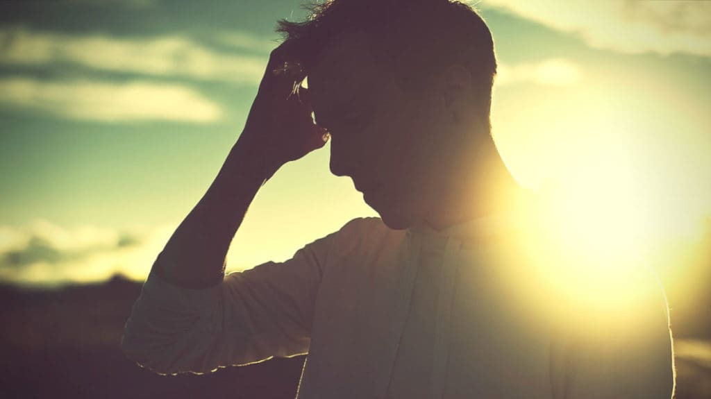 Man standing in from of setting sun