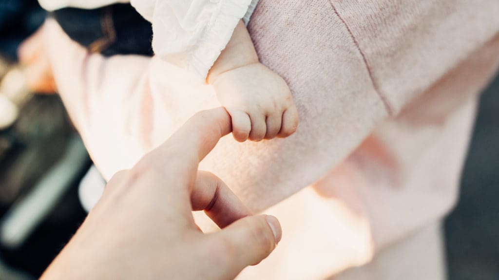 Baby holding parent's finger