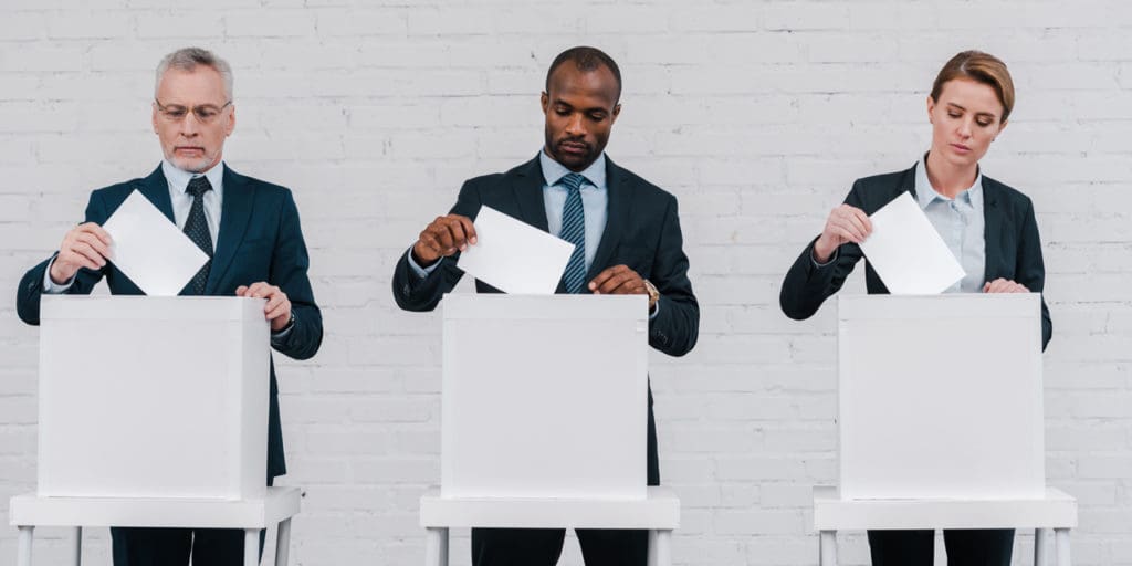 Three adults at voting booths