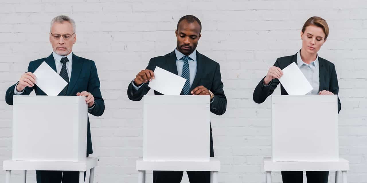 Three adults at voting booths