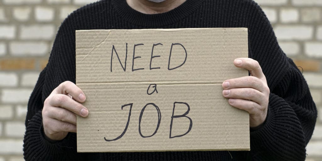 Man holding a sign saying "need a job"
