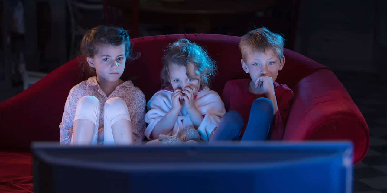 Three kids watching TV