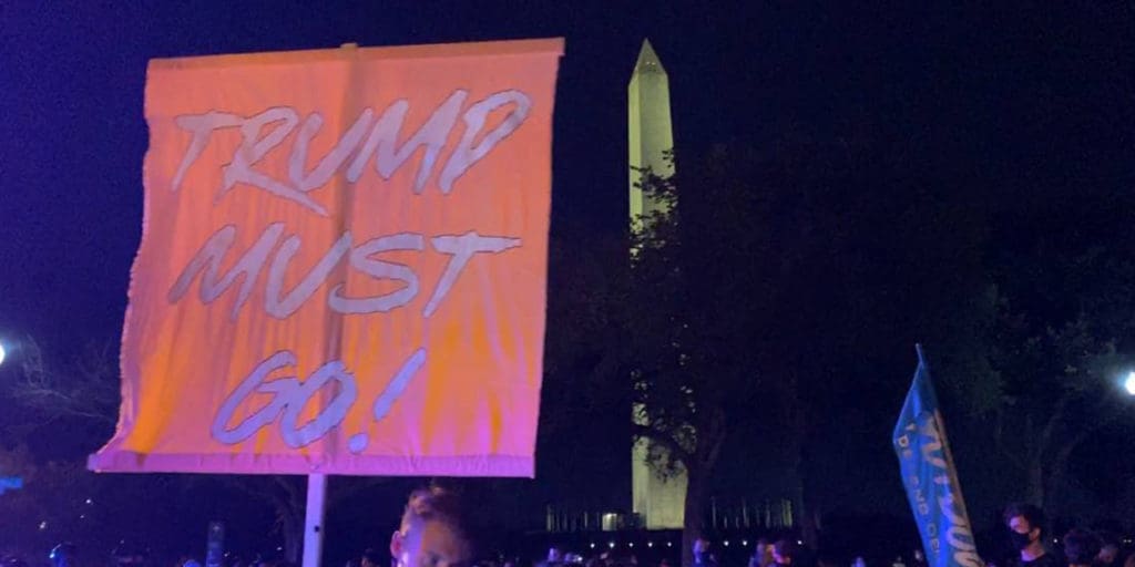 Protest sign says "Trump Must Go"