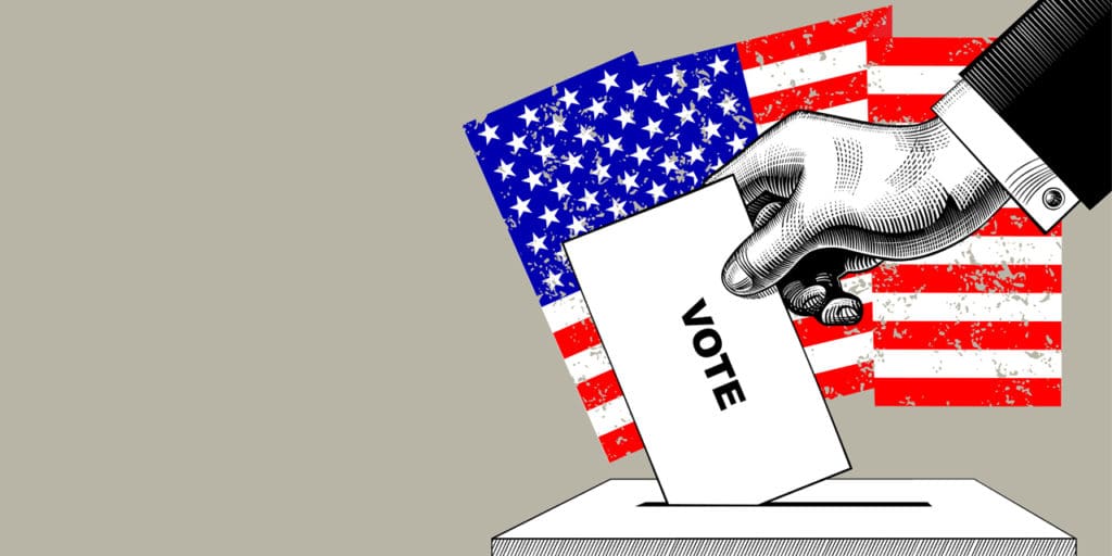 A hand placing a ballot in a ballot box|