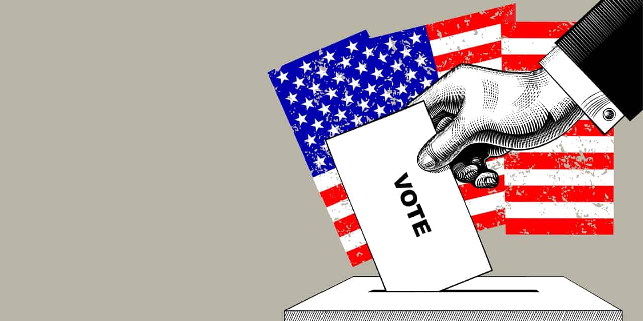 A hand placing a ballot in a ballot box|