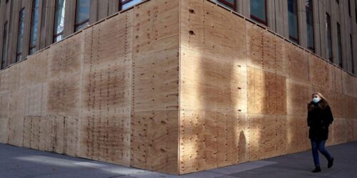 People walk past the boarded up Empire State Building building in anticipation of the elections