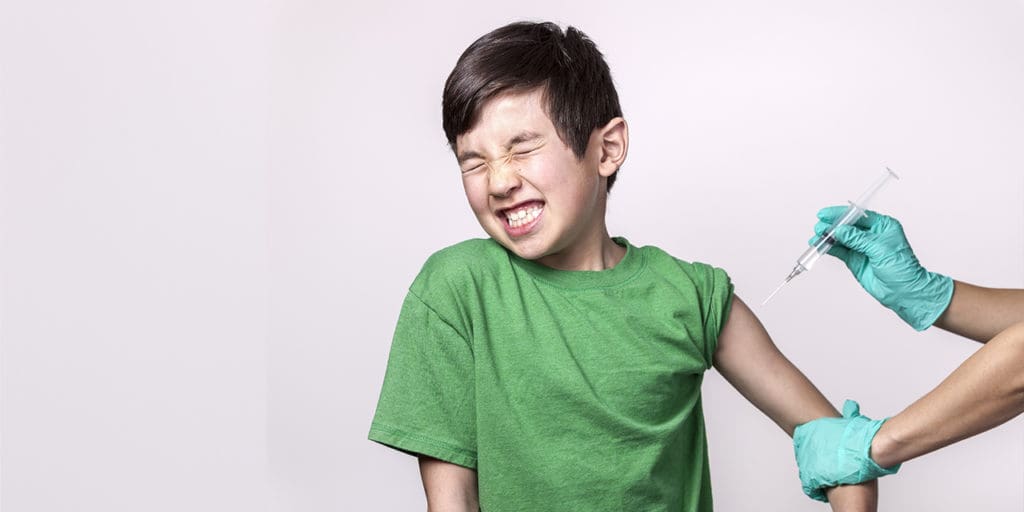 young boy in a green t-shirt getting a shot in the arm