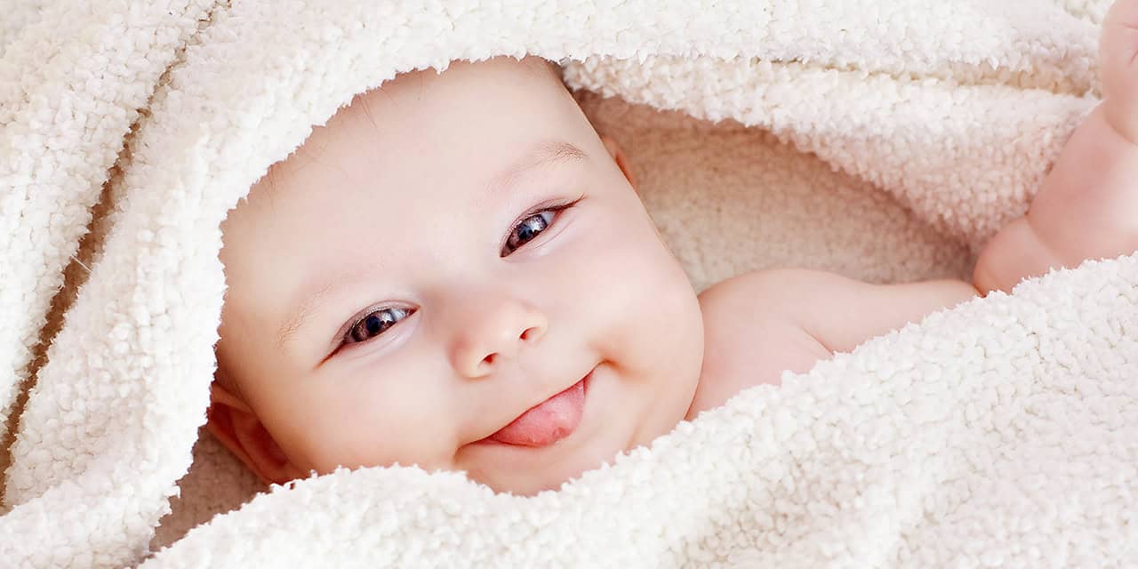 Cute baby smiling while snuggled in a blanket