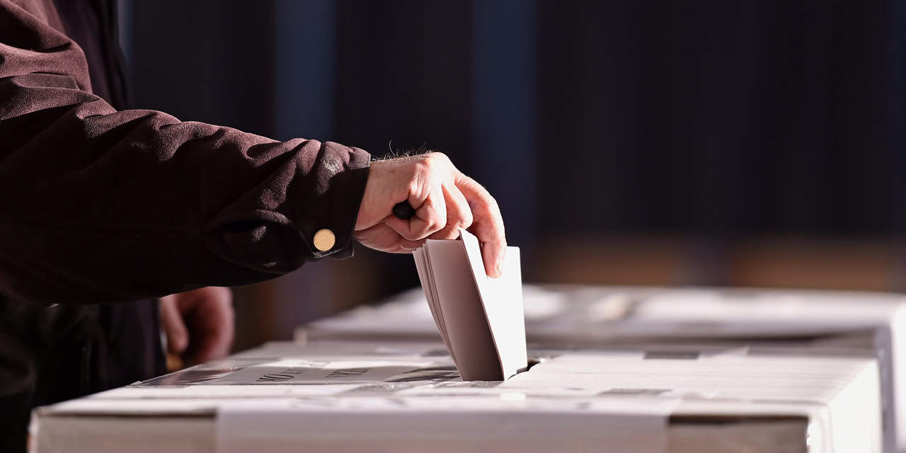 Man dropping election ballot into a ballot box